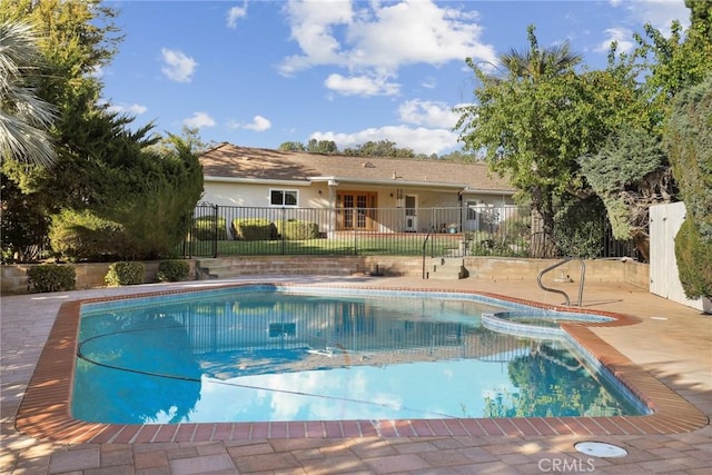 view of pool featuring a patio area, a pool with connected hot tub, and fence