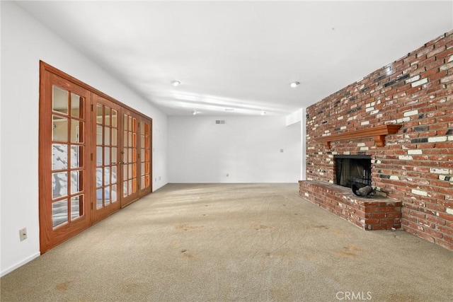 unfurnished living room with visible vents, a fireplace, french doors, and carpet floors