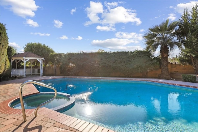 view of swimming pool with a gazebo, fence, and a pool with connected hot tub