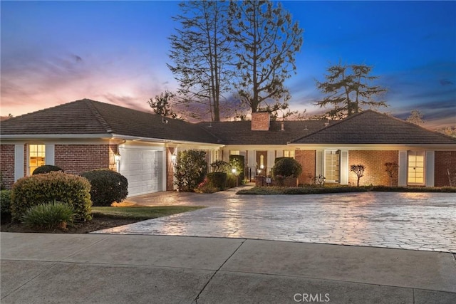 ranch-style house with brick siding, driveway, an attached garage, and a tiled roof