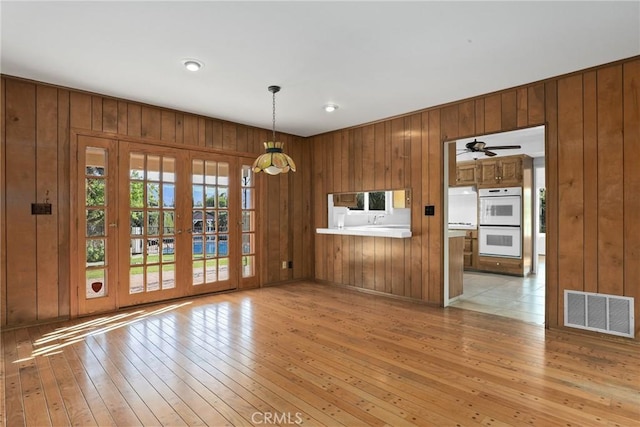 unfurnished dining area with light wood finished floors, visible vents, and wooden walls