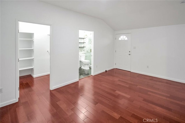 foyer entrance with vaulted ceiling, wood finished floors, and baseboards