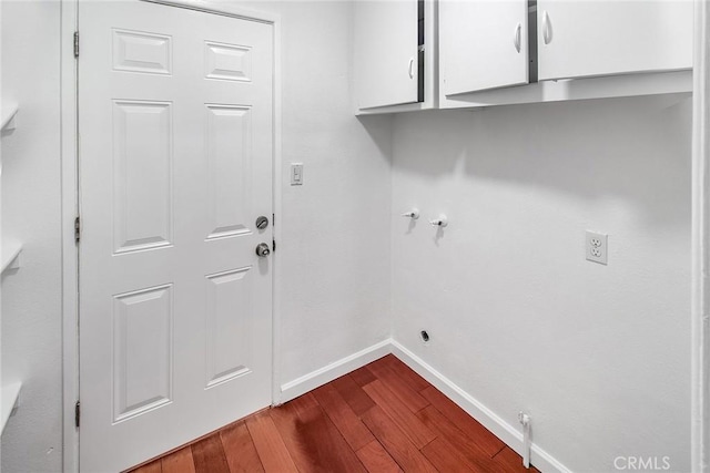 washroom featuring baseboards, gas dryer hookup, hookup for an electric dryer, cabinet space, and dark wood-type flooring