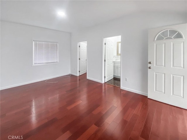 unfurnished bedroom with baseboards, ensuite bathroom, and dark wood-style flooring