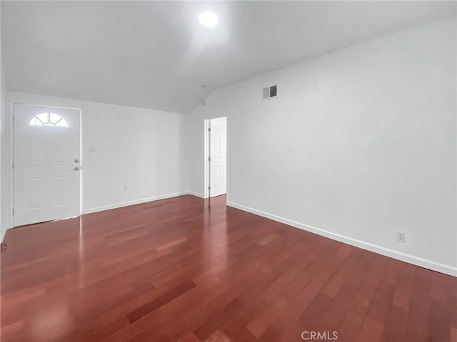 spare room featuring visible vents, baseboards, lofted ceiling, and wood finished floors