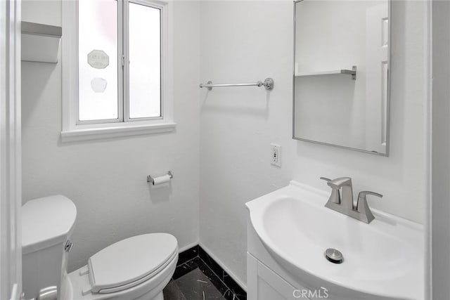 bathroom with toilet, vanity, and baseboards