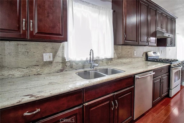 kitchen with backsplash, under cabinet range hood, dark wood finished floors, stainless steel appliances, and a sink