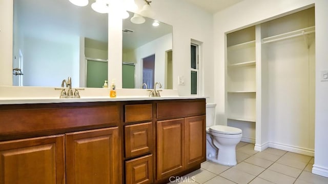 bathroom with double vanity, a stall shower, a sink, tile patterned flooring, and toilet