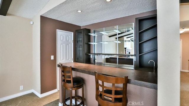 kitchen with a textured ceiling, baseboards, and carpet floors