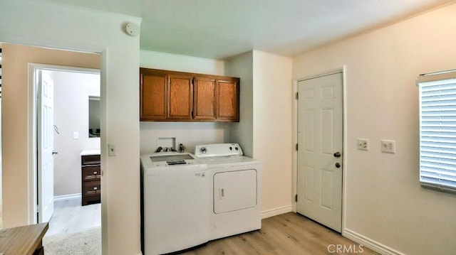 laundry room with washer and dryer, baseboards, cabinet space, and light wood finished floors