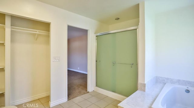 full bathroom featuring tile patterned floors, a garden tub, a spacious closet, and a shower stall