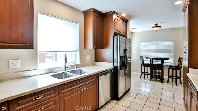 kitchen with light tile patterned floors, baseboards, a sink, stainless steel appliances, and light countertops