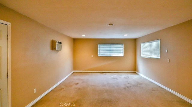 unfurnished room with light carpet, a wall mounted air conditioner, and baseboards