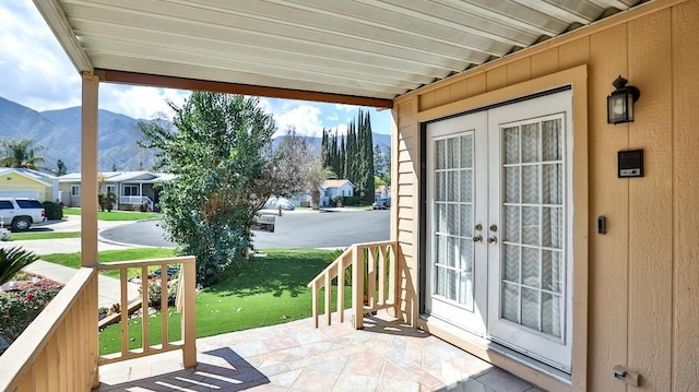 entryway featuring a mountain view, a residential view, wooden walls, and french doors