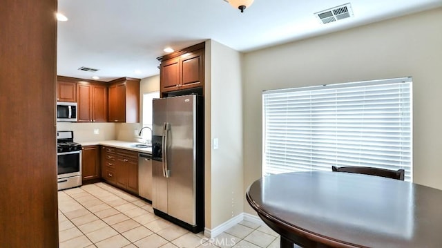 kitchen with a sink, light tile patterned flooring, visible vents, and stainless steel appliances