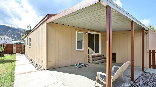 view of side of property with a mountain view, entry steps, a patio, and fence