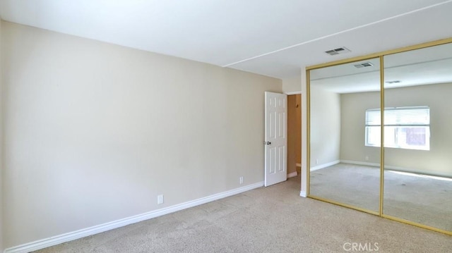 unfurnished bedroom featuring carpet, visible vents, a closet, and baseboards