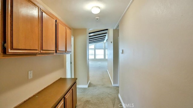 hall featuring light colored carpet and baseboards