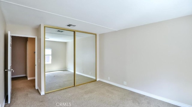 unfurnished bedroom featuring visible vents, carpet flooring, baseboards, and a closet