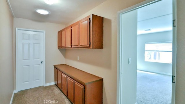 interior space featuring light colored carpet and baseboards