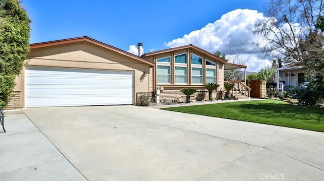 view of front of property featuring a front yard, concrete driveway, and an attached garage