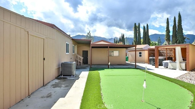 back of property with a patio, a mountain view, and central AC