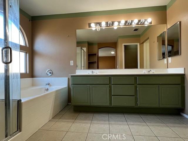 full bathroom featuring tile patterned floors, a garden tub, a sink, a shower stall, and double vanity