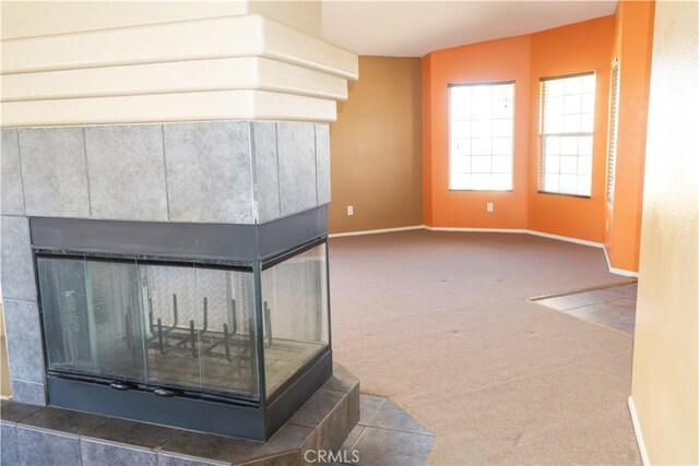 detailed view of a tiled fireplace, carpet, and baseboards