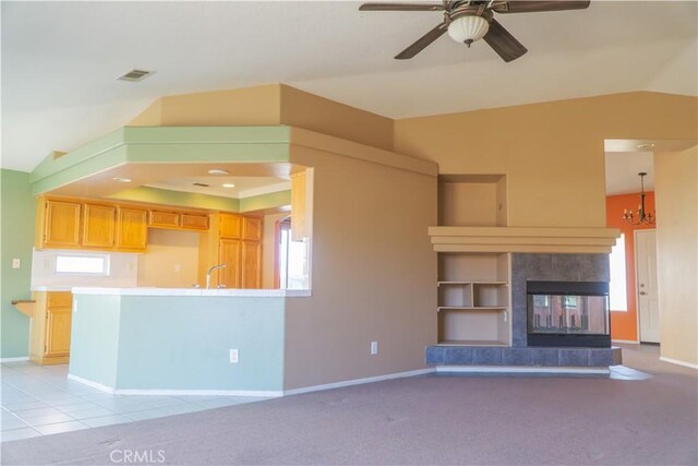 unfurnished living room with baseboards, a sink, a ceiling fan, vaulted ceiling, and a chandelier