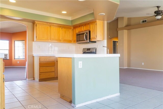 kitchen with stainless steel microwave, arched walkways, tile countertops, light tile patterned flooring, and ceiling fan