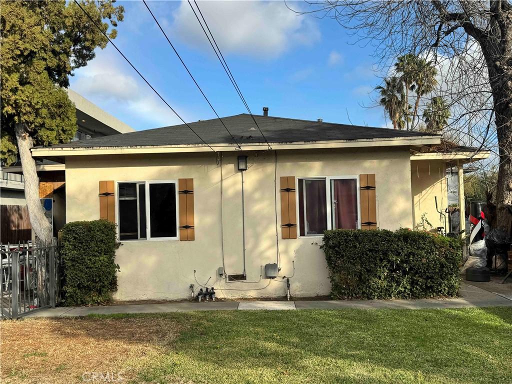 rear view of house with stucco siding and a lawn