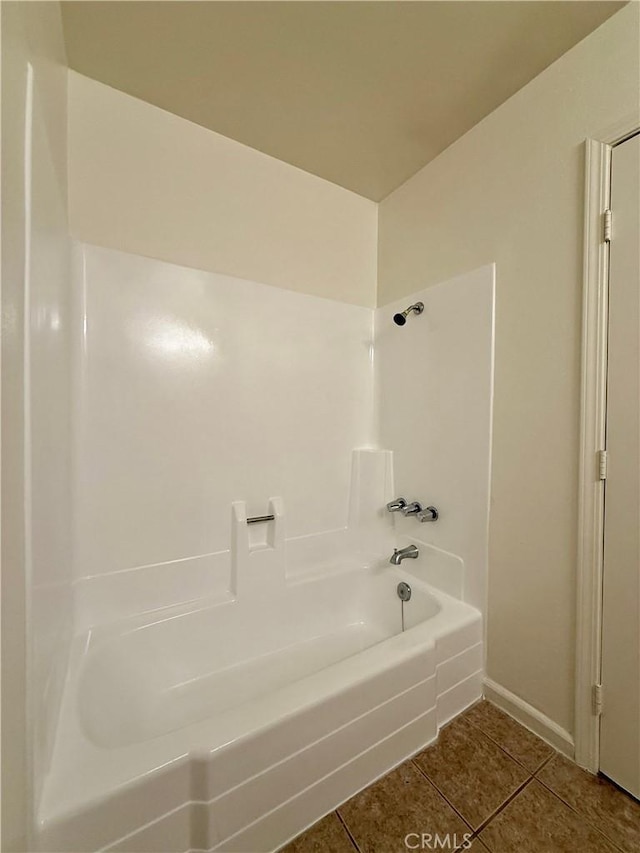 bathroom featuring tile patterned flooring, washtub / shower combination, and baseboards