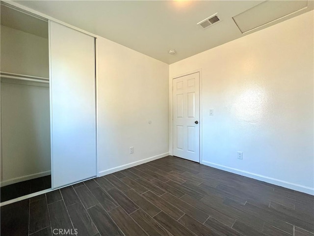 unfurnished bedroom featuring a closet, visible vents, dark wood-type flooring, and baseboards