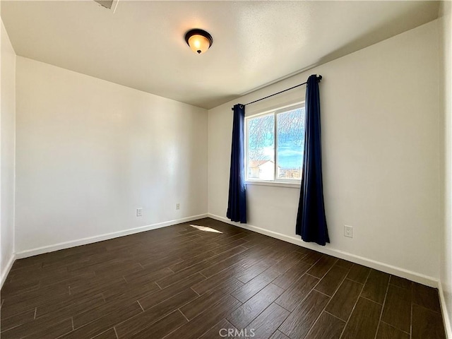 unfurnished room featuring baseboards and dark wood-style floors