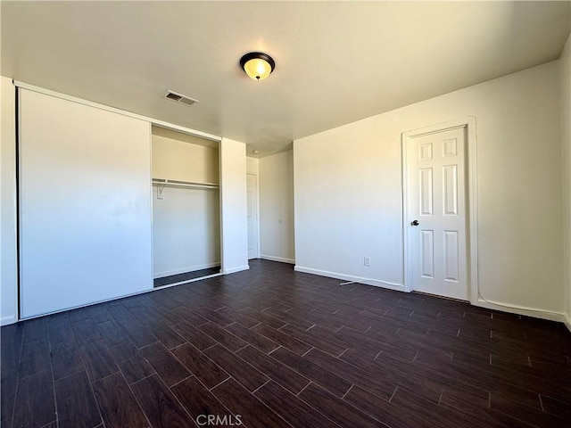 unfurnished bedroom with dark wood finished floors, visible vents, baseboards, and a closet