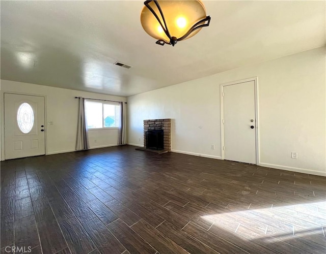 unfurnished living room with visible vents, a fireplace, dark wood-type flooring, and baseboards