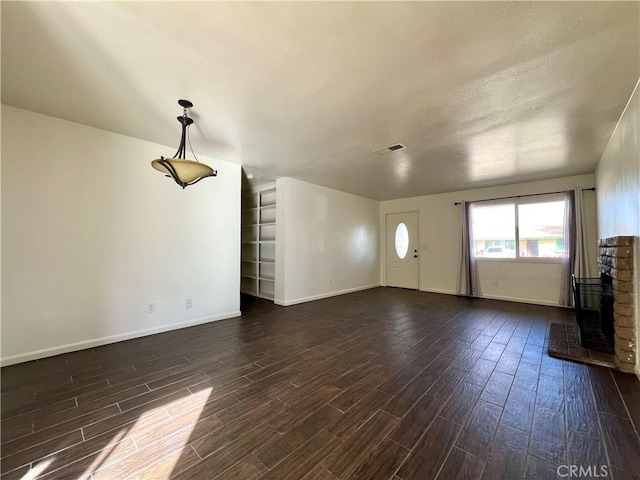 unfurnished living room featuring visible vents, dark wood-type flooring, and baseboards