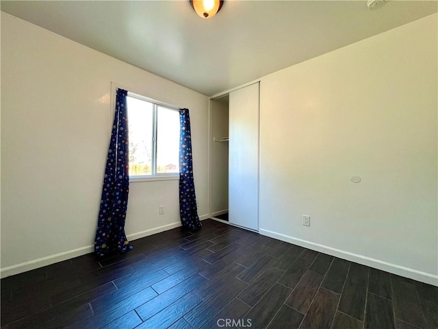 spare room with baseboards and dark wood finished floors