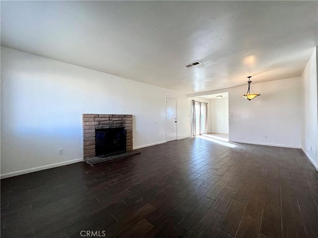 unfurnished living room featuring visible vents, baseboards, a brick fireplace, and dark wood-style floors