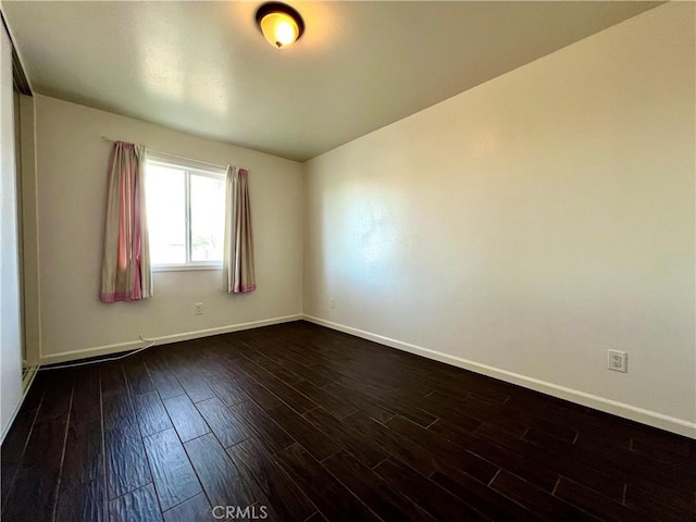 empty room with dark wood-style floors and baseboards