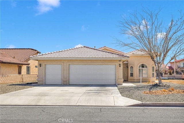 mediterranean / spanish-style house featuring stucco siding, a tile roof, fence, concrete driveway, and a garage