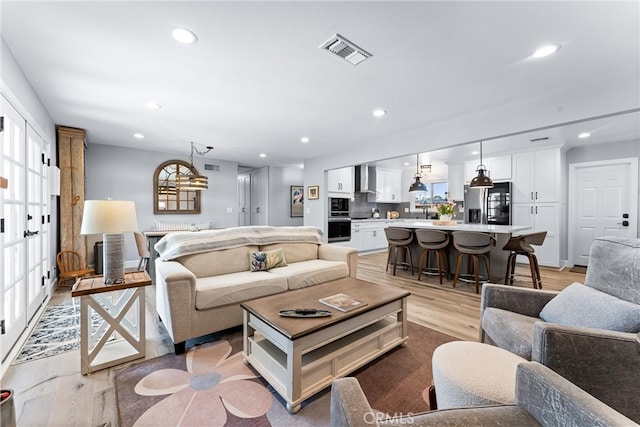 living room with light wood finished floors, visible vents, and recessed lighting