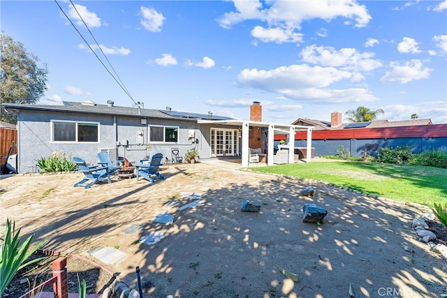 rear view of property with a patio, an outdoor fire pit, a yard, a fenced backyard, and french doors