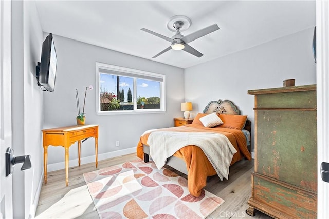 bedroom with a ceiling fan, wood finished floors, and baseboards