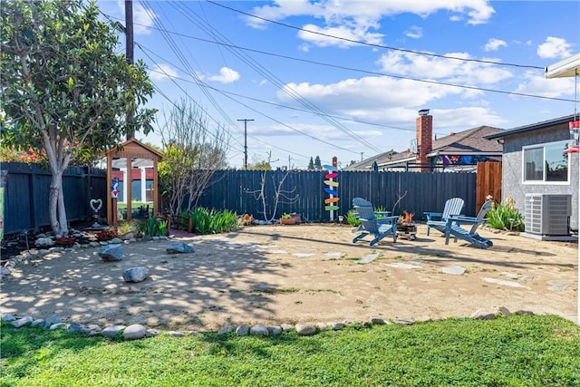 view of yard featuring a patio area, central AC unit, a fenced backyard, and an outdoor fire pit