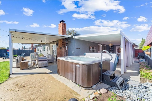 rear view of property with fence, an outdoor living space, a chimney, a hot tub, and a patio area