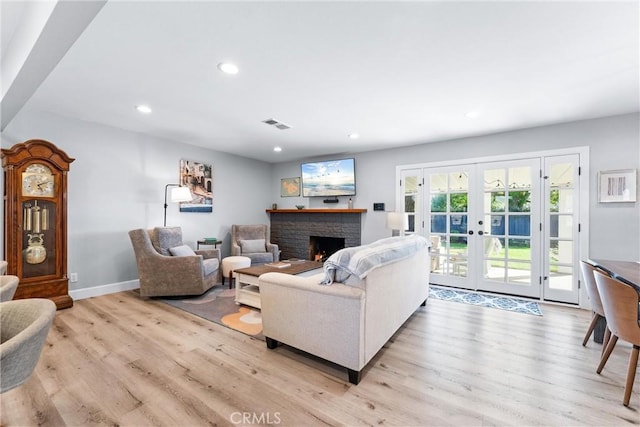 living area featuring recessed lighting, light wood-style flooring, french doors, and a fireplace