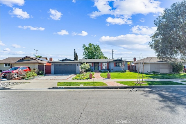 view of front of home with driveway, a front lawn, fence, a residential view, and an attached garage