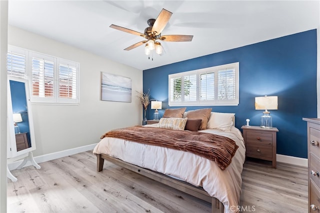 bedroom with baseboards, multiple windows, and light wood finished floors