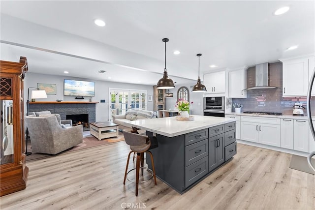 kitchen with a fireplace, gray cabinetry, stainless steel appliances, white cabinetry, and wall chimney exhaust hood